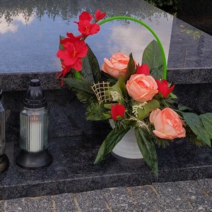 Uporządkowany grób, złożone kwiaty i zapalone znicze